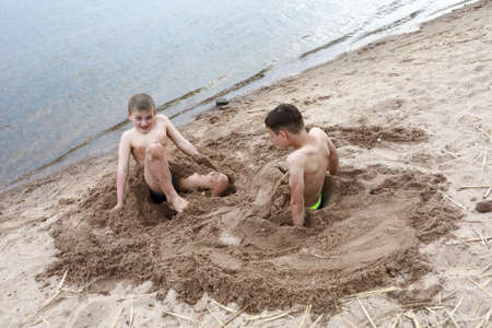 Two boys play on sandy beach of Lake Seliger, Ostashkov, Russiaの写真素材