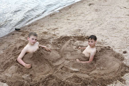 Two boys play on sandy beach of Lake Seliger, Ostashkov, Russiaの写真素材