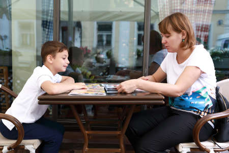 Mother and son with menu books on terrace of restaurantの写真素材