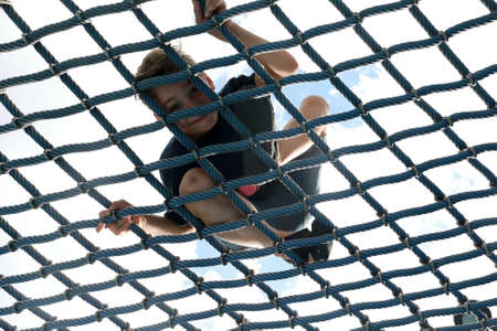 Boy training over netting obstacle course in park