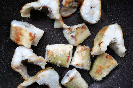 Pieces of fried navaga fish in pan