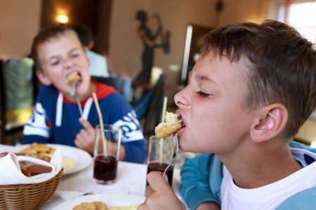 Two boys eating nuggets in a restaurantの写真素材