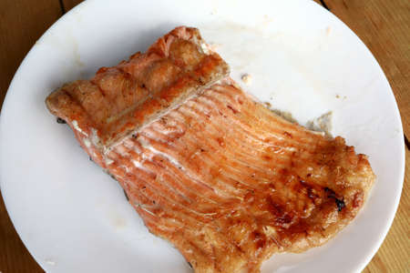 White plate with grilled trout on wooden table