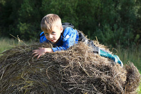 Child climbing onto stack of straw, Kareliaの写真素材