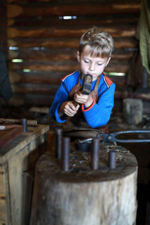 Boy learning to work with hammer in forgeの写真素材