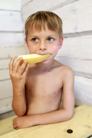 Portrait of boy eating melon at homeの写真素材