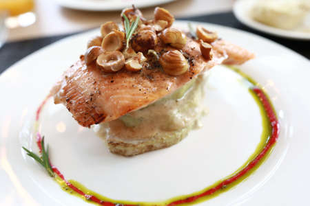 Trout with nuts and zucchini on plate in restaurant