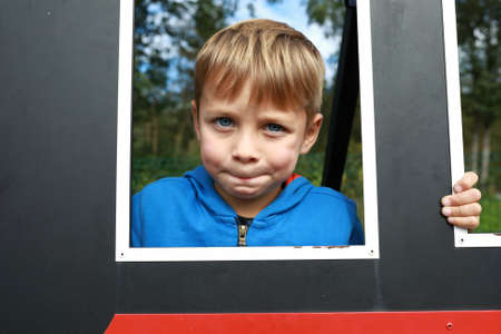 Child face in plywood frame in summer