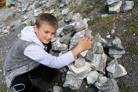 Child putting stones in heap in marble canyon, Kareliaの写真素材