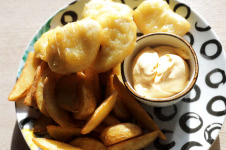Chicken nuggets with fried potatoes on plate