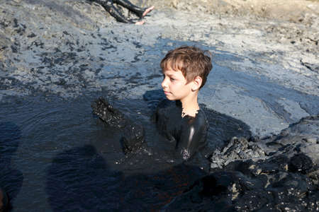 Child sitting in medicinal mud, Krasnodar region, Russia