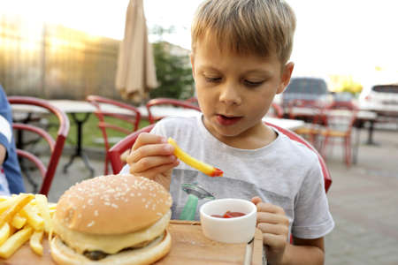 Child eating fries with ketchup in restaurantの写真素材