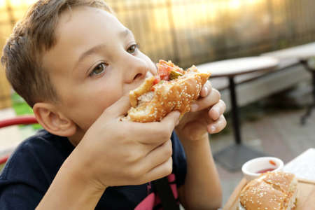 Child eating burger in an outdoor restaurantの写真素材