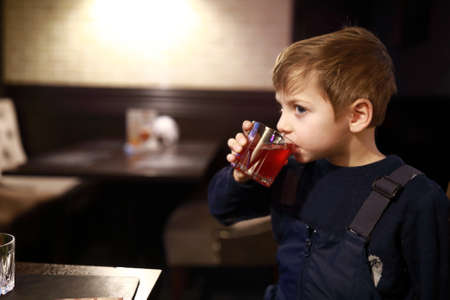 Portrait of kid drinking juice in restaurantの写真素材