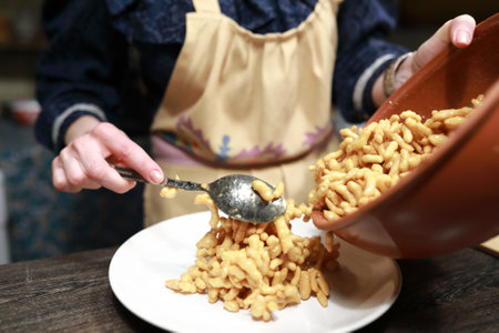 Woman puts chak-chak on plate in kitchen