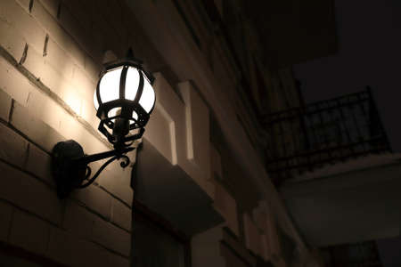 Lantern on wall of building at nightの写真素材