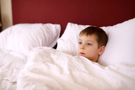 Child lying in bed in the morningの写真素材