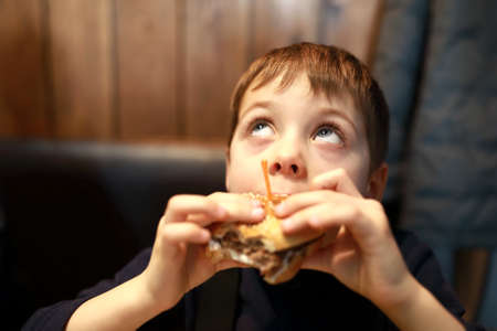 Portrait of boy eating burger in restaurantの写真素材