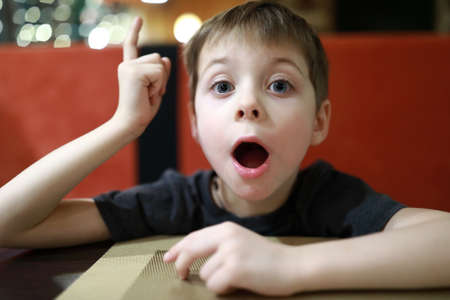 Portrait of boy having eureka moment in cafeの写真素材