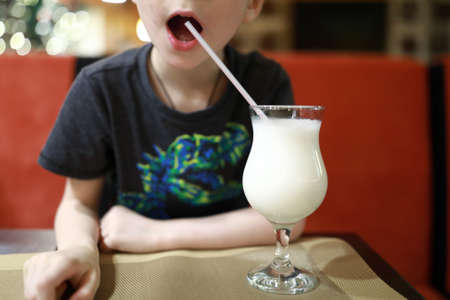 Child drinking milk shake in a restaurantの写真素材