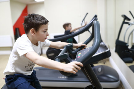 Child exercising on stationary bike in gymの写真素材