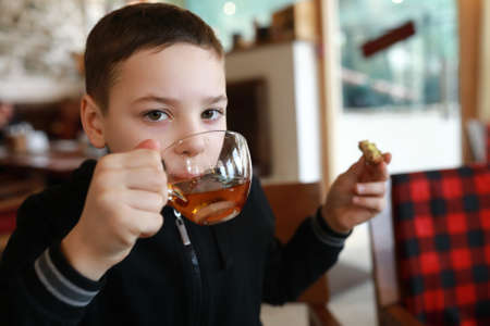 Boy has tea with bun in restaurantの写真素材