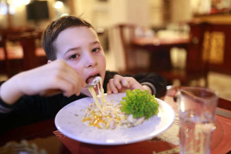 Child eating pasta bolognese in a restaurantの写真素材