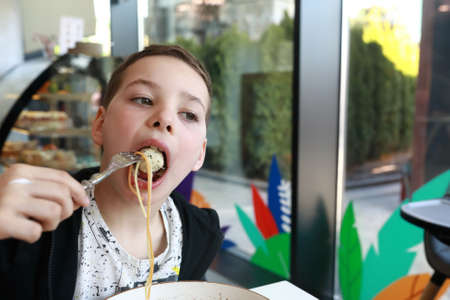 Child eating chicken meatballs with spaghetti in restaurantの写真素材