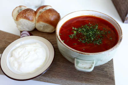 Bowl of borscht with sour cream and buns in restaurantの写真素材