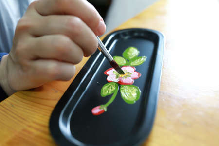 Person painting tray at table in workshop