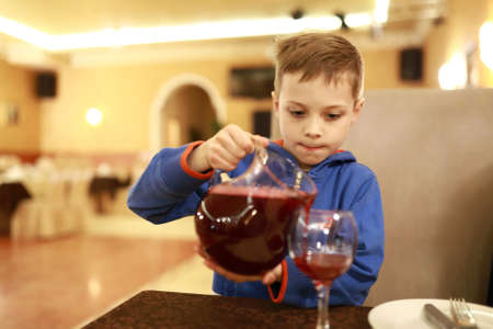 Portrait of boy pouring juice in restaurantの写真素材