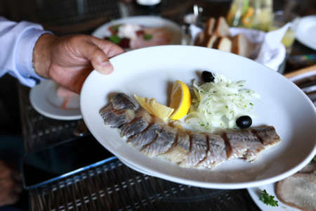 Person holding plate of salted herring in restaurantの写真素材