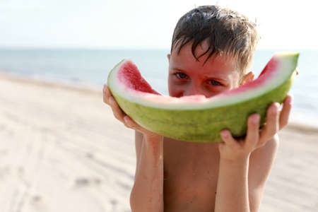 Boy eating watermelon on beach of Azov sea in summerの写真素材
