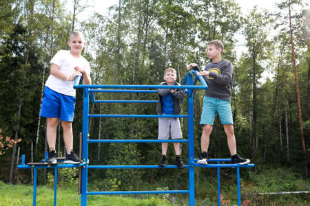 Three boys playing in outdoor playground in summer