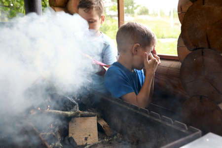 Two children kindle firewood on grill in gazebo, Kareliaの写真素材