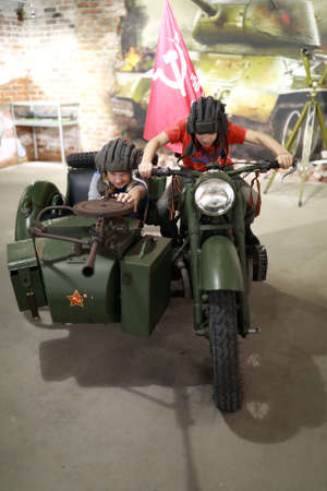 Children playing on military motorcycle M-72 indoorの写真素材