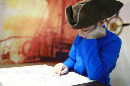 Portrait of kid in cocked hat examines mapの写真素材