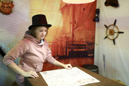 Portrait of woman in top hat examines mapの写真素材
