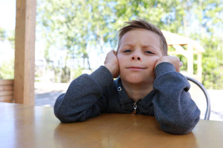 Pensive boy waiting food at table in restaurantの写真素材