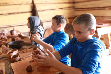 Three kids make clay crafts in workshopの写真素材