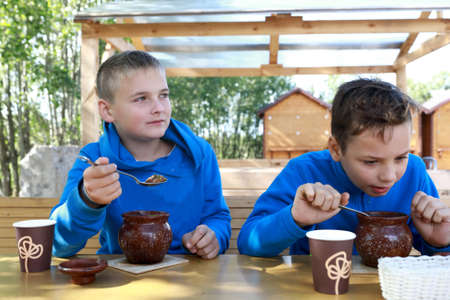 Two boys eating pot roast in restaurantの写真素材