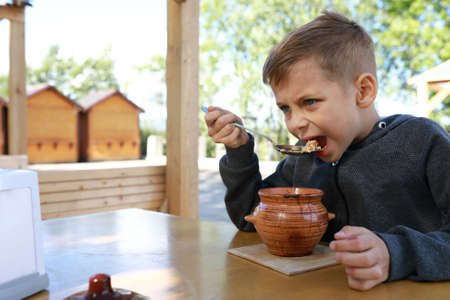 Hungry child eating pot roast in restaurantの写真素材