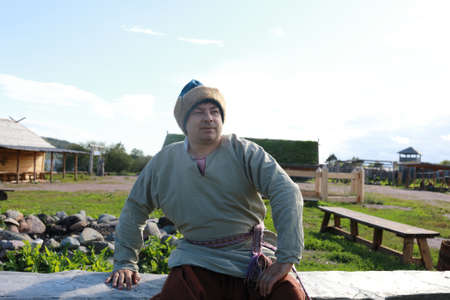 Man in Scandinavian folk clothes on bench, Kareliaの写真素材