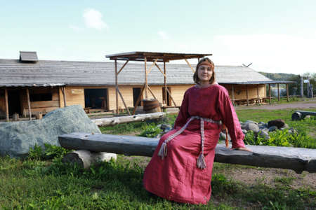 Woman in Scandinavian folk clothes on bench, Kareliaの写真素材