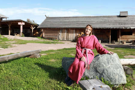 Woman in Scandinavian folk clothes on stone, Kareliaの写真素材