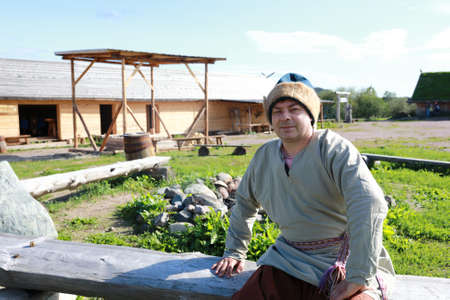 Man in Scandinavian folk clothes sitting on bench, Kareliaの写真素材
