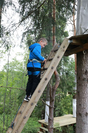 Child climbs stairs to obstacle course in rope parkの写真素材