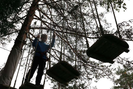 Boy overcomes obstacle course in rope parkの写真素材