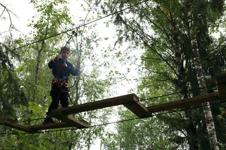 Serious kid overcomes obstacle course in rope parkの写真素材