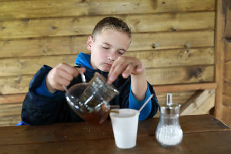 Boy pouring herbal tea on restaurant terraceの写真素材